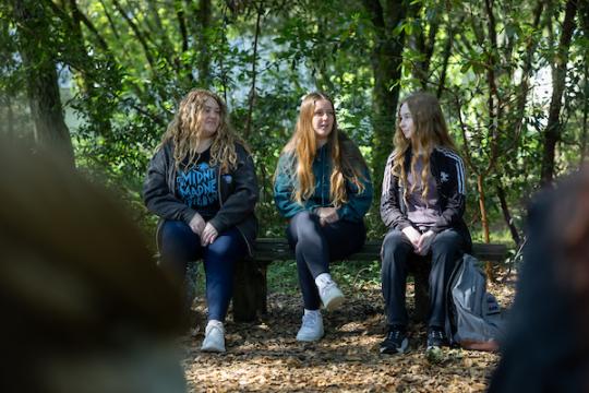 three students sitting on bench