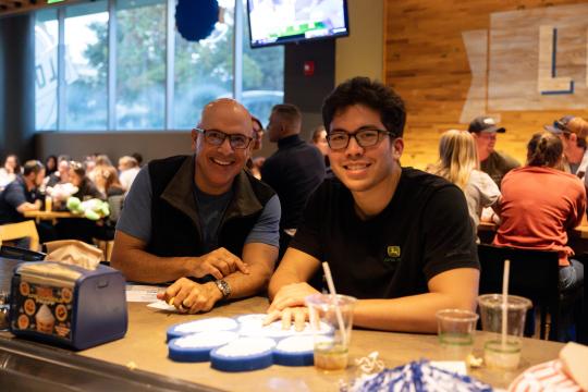 Two people smile at the camera while playing a game