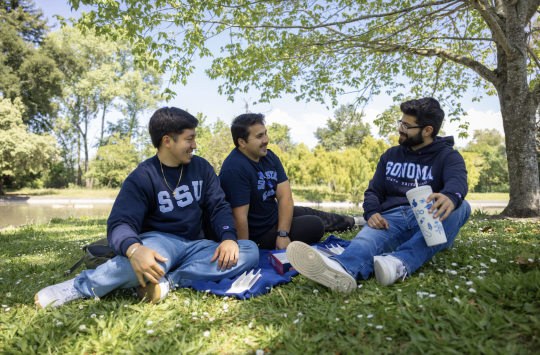 Three students laugh and talk by the lakes
