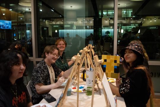 Students smile and hold up Minecraft-themed paintings