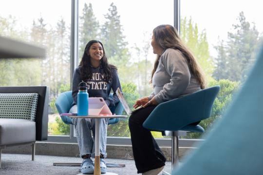 Two students sit and talk in the Wine Spectator Learning Center