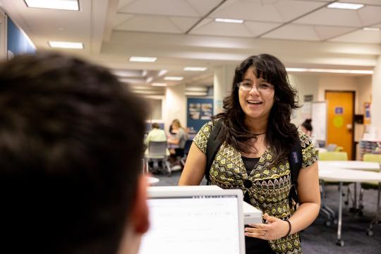 Someone speaks with a student at an info desk