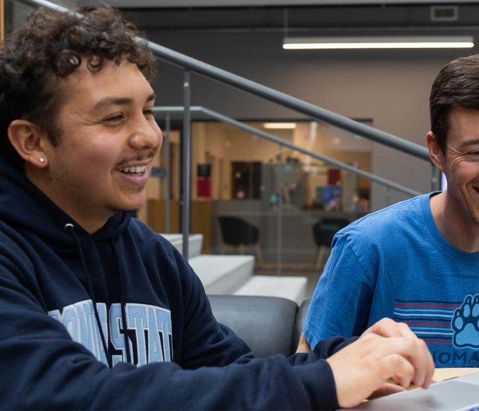 Two students looking at a computer smiling