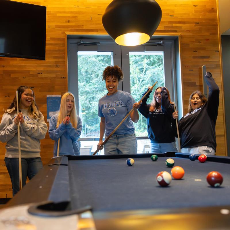 Group of students playing pool and cheering