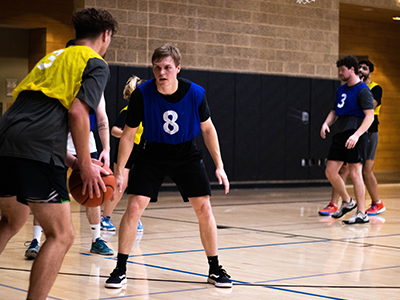 Intramural baskeball game, one students has the ball and another student is defending