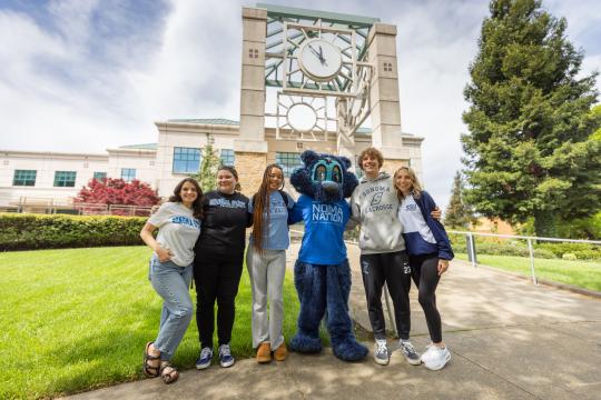 Students hugging Lobo in front of the library