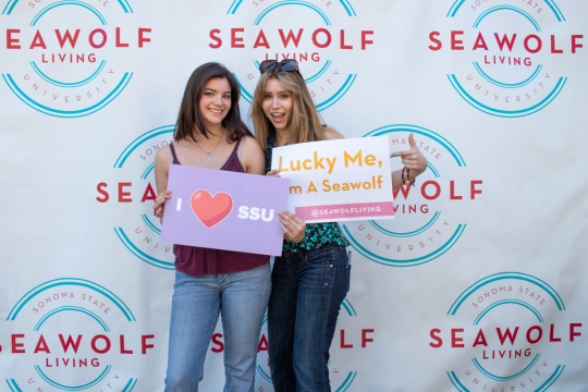 2 students taking a photo holding ssu signs