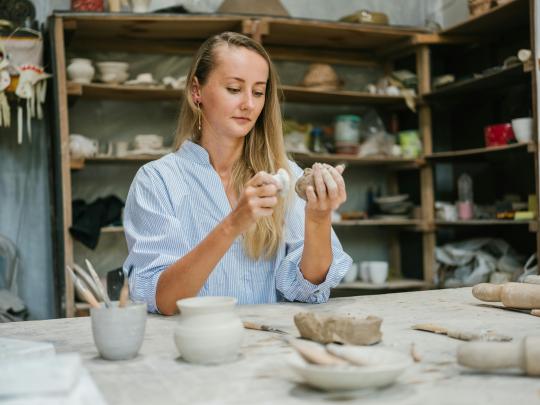 student using clay to do pottery