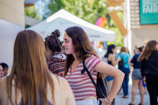 Student standing at a table talking to another student
