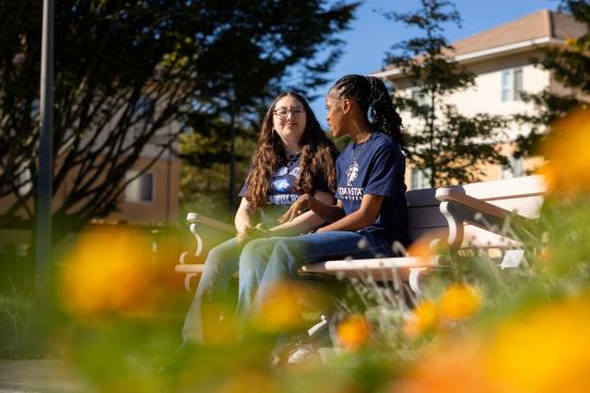 Two friends on a bench with flowers pictured
